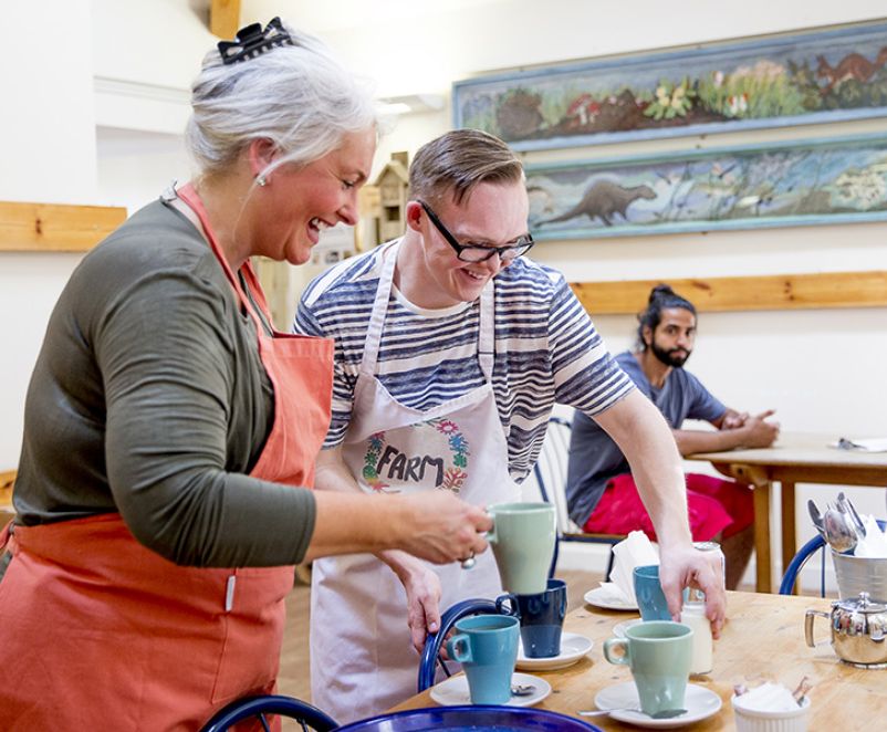 Photo of a male and female working in a café setting a table